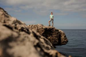 Randonneur accompagner: Fille sur le rocher avec des bâtons de marche sur le beau fond de la mer et ciel clair à Chypre