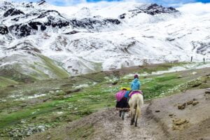 Trek au Pérou : un cheval et des péruviens devant une montagne enneigée Akaoka