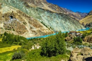 Voyage Inde circuit Himalaya : une rivière bleu ciel au milieu d'un village himalayen, un paysage montagneux.