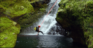 Weekend canyoning Hérault : Un homme qui escalade une montagne canoë dans le lac