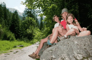 Une femme et deux filles assies sur une roche entoure d’arbres, Cevennes avec un âne